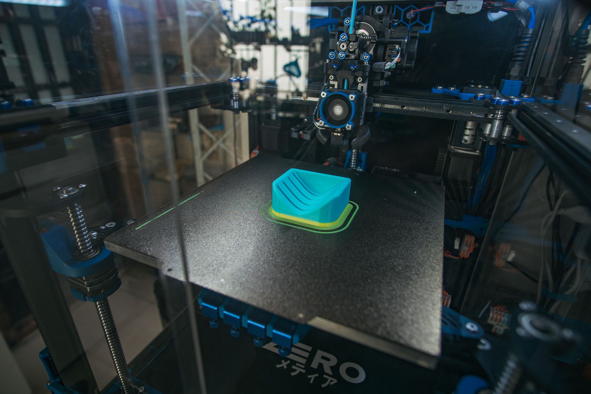 3D printer in operation building a plastic part, in a workshop setting