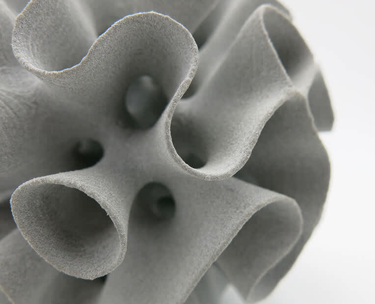 Close-up of a light gray SLS or MJF printed part showing the powder-finished surface texture